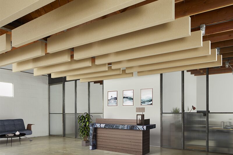 Reception desk under beige acoustic baffles
